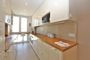 a kitchen with white cabinets and a wooden counter top at Estepona Port Luxury Apartment AURA in Estepona