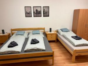 two twin beds in a room with three pictures on the wall at Kondé Apartments D in Dunajská Streda