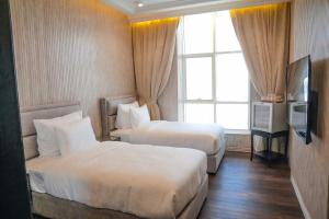 a hotel room with two beds and a television at M14 Hotel Apartment in Ras al Khaimah