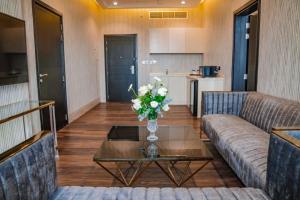 uma sala de estar com um sofá e uma mesa com flores em M14 Hotel Apartment em Ras al-Khaimah