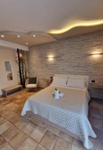 a bedroom with a large white bed and a brick wall at Hotel La Rocca in San Marino