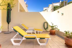 un patio con plantas y sillas amarillas y blancas en Casa Amiga en Carvoeiro