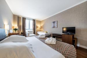 オルメドにあるCastilla Termal Olmedoのベッド2台、薄型テレビが備わるホテルルームです。