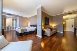 オルメドにあるCastilla Termal Olmedoのベッド2台とソファが備わるホテルルームです。