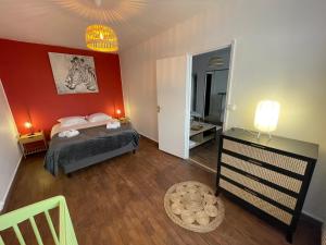 a bedroom with a bed and a red wall at Tegmen, Joli appartement au calme in Caen