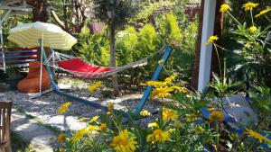 una hamaca y una sombrilla en un jardín con flores en Mila Pansiyon, en Cıralı