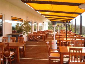 een restaurant met houten tafels en stoelen en gele parasols bij Hotel und Gasthaus Rammelburg-Blick in Friesdorf