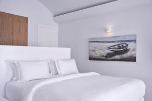 a bedroom with two beds and a painting on the wall at White Sand Suites Mykonos in Mikonos