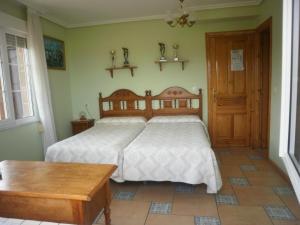 a bedroom with a large bed and a wooden table at Pensión Galimar in San Vicente de la Barquera