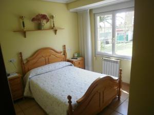 1 dormitorio con cama de madera y ventana en Pensión Galimar, en San Vicente de la Barquera