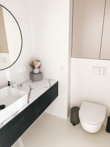 a white bathroom with a sink and a toilet at Genio apartamentai Kunigiskiuose in Palanga