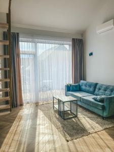 a living room with a blue couch and a table at Genio apartamentai Kunigiskiuose in Palanga