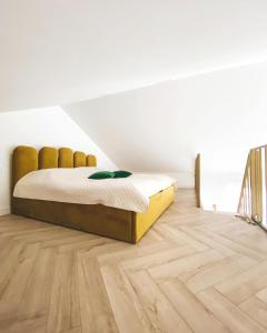 a bedroom with a bed and a wooden floor at Genio apartamentai Kunigiskiuose in Palanga