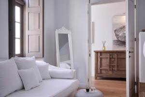 a white living room with a white couch and a mirror at White Sand Suites Mykonos in Mikonos