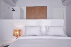 a white bedroom with a white bed with two pillows at White Sand Suites Mykonos in Mikonos