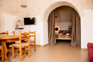 a dining room with a table and a bedroom at Pavì Trulli e Suites in Locorotondo