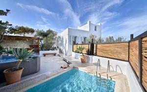 een achtertuin met een zwembad en een wit huis bij Villa Mykonos Heaven - Sea View & Outdoor Hot Tub in Mykonos-stad