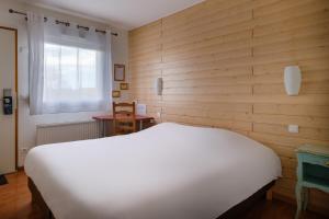 een slaapkamer met een wit bed en een houten muur bij Eqynox Hotel in Vitry-le-François