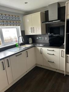 cocina con armarios blancos, fregadero y ventana en Dyce Flat - Near Airport, en Dyce