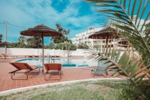 a pool with chairs and umbrellas and a hotel at Casa Velha Apartments - Adults friendly in Albufeira
