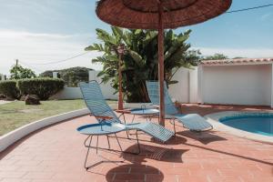 two chairs and an umbrella next to a pool at Casa Velha Apartments - Adults friendly in Albufeira