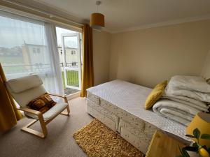 a bedroom with a bed and a chair and a window at 124, Three bed two storey chalet on Bermuda holiday park, Hemsby - Sleeps 7, bed linen and towels included with onsite entertainment and further entertainment close by - includes balcony in Great Yarmouth