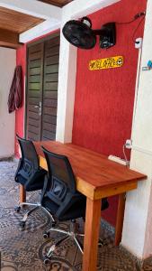 a wooden table with a chair in front of a wall at Tropical Hostel in Pipa