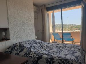 sypialnia z łóżkiem i oknem z krzesłami w obiekcie 3 pièces face mer et St-Tropez w mieście Cogolin