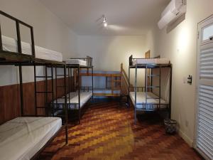 a room with three bunk beds in a room with a wooden floor at Hostel do Lago in Sao Jose do Rio Preto