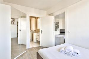 een slaapkamer met witte muren en een bed met spiegels bij Charming flat with balcony at the doors of Paris - Welkeys in La Courneuve
