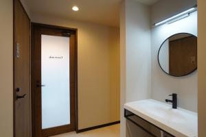 W łazience znajduje się lustro i umywalka. w obiekcie KIIIYA cafe&hostel w mieście Azumino
