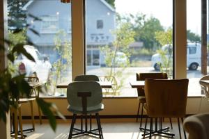 una stanza con tavoli e sedie di fronte a una finestra di KIIIYA cafe&hostel ad Azumino