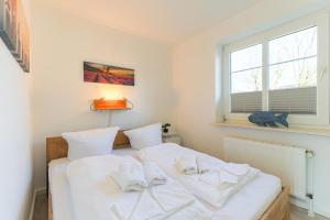 sypialnia z łóżkiem z białą pościelą i poduszkami w obiekcie Appartement Weststrand w mieście Westerland
