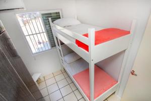 Ce lit superposé se trouve dans une petite chambre dotée d'étagères rouges. dans l'établissement Residencial Primavera, à Bombinhas