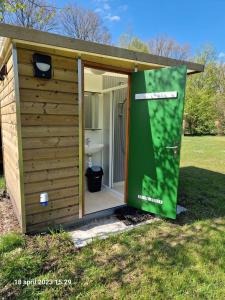 a shed with a door open in a yard at Lege Kampeerplaats + Prive Sanitair, Camping Alkenhaer in Appelscha