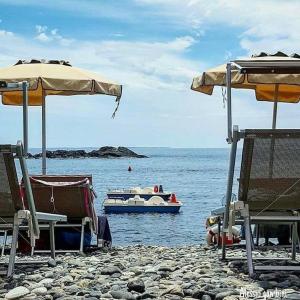a boat in the water with chairs and umbrellas on a beach at Casa Alessandra in Pomonte