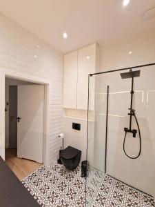 a bathroom with a shower and a black stool on a rug at Apartamenty nad Zalewem Zegrzynskim z tarasem 23 m2 in Serock