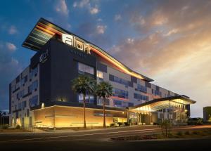 a hotel with a building with palm trees in front of it at Aloft Henderson in Las Vegas