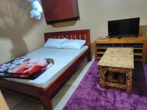 a bedroom with a bed and a tv and a table at Ella's Haven in Nairobi