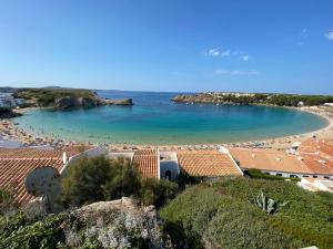 een uitzicht op een strand met mensen in het water bij La Casa del Jardin. Menorca in Punta Grossa