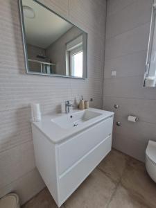 uma casa de banho branca com um lavatório e um espelho em Deluxe Apartment Mila em Nin