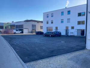 un estacionamiento con autos estacionados frente a un edificio en SITE.INN Denkendorf en Denkendorf