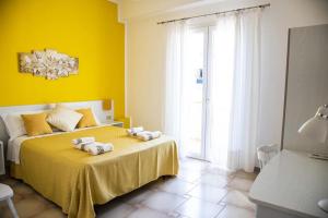 a yellow bedroom with a bed with towels on it at Blu Mare Lampedusa Bed And Breakfast in Lampedusa