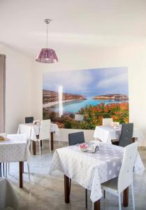 un ristorante con tavoli e sedie bianchi e un dipinto di Blu Mare Lampedusa Bed And Breakfast a Lampedusa