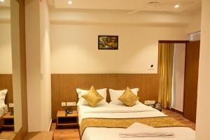 a hotel room with a bed with white sheets and gold pillows at GRAND ONE TOWER in Chennai