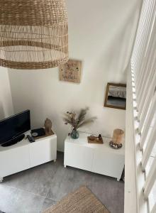 a living room with two white tables and a television at La maison du Clos in Valras-Plage