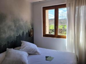 Dormitorio con cama con ventana y libro en Maison Les Glycines, en Vieille-Brioude