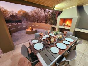 un patio con mesa de comedor y sillas y chimenea en Kudus Crest Bush Retreat, en Marloth Park
