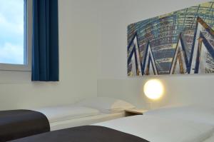1 Schlafzimmer mit 2 Betten und einem Fenster in der Unterkunft B&B Hotel Leipzig-Nord in Leipzig