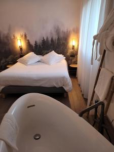 Hotel Les Glycines في Vieille-Brioude: غرفة نوم مع سرير وحوض استحمام بجانب سرير